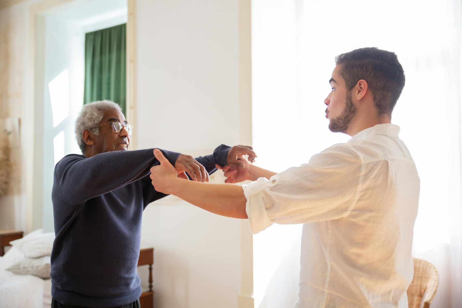 A caregiver supporting an older adult during gentle exercise at home